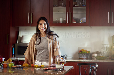 Buy stock photo Portrait of a happy young woman preparing a meal in her kitchen at home
