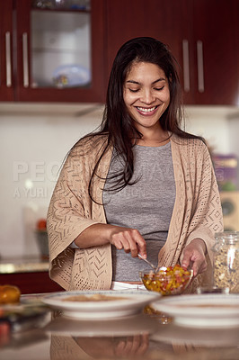 Buy stock photo Shot of a happy young woman preparing a meal in her kitchen at home