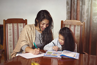 Buy stock photo Shot of a mother watching her daughter do her homework at home