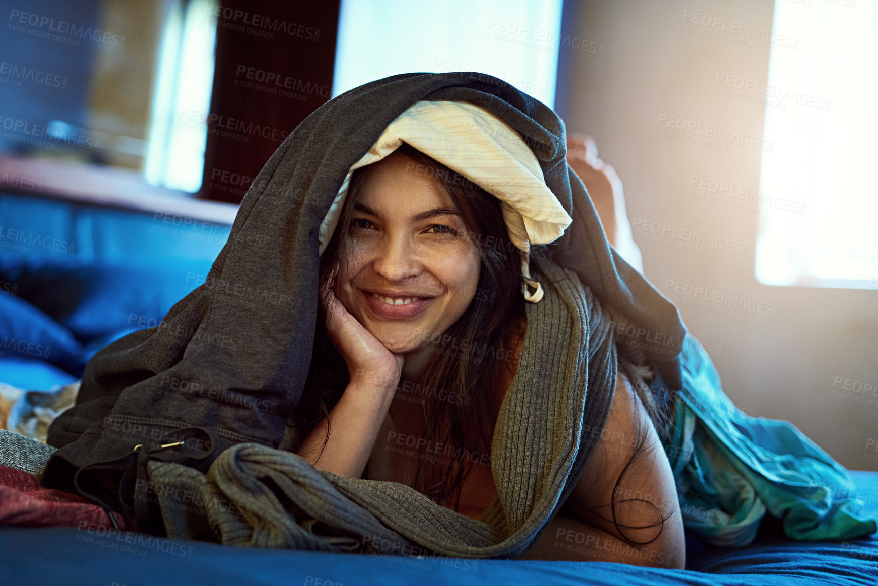 Buy stock photo Clothes, stack and portrait of woman on bed for spring cleaning, lazy and laundry day at home. Happy, female person and face with fabric material in house for messy, comfort and break in housekeeping