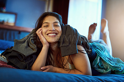 Buy stock photo Portrait of a happy young woman lying under a pile of clothes on her bed