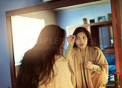 Buy stock photo Shot of a young woman examining her hair carefully in a mirror at home
