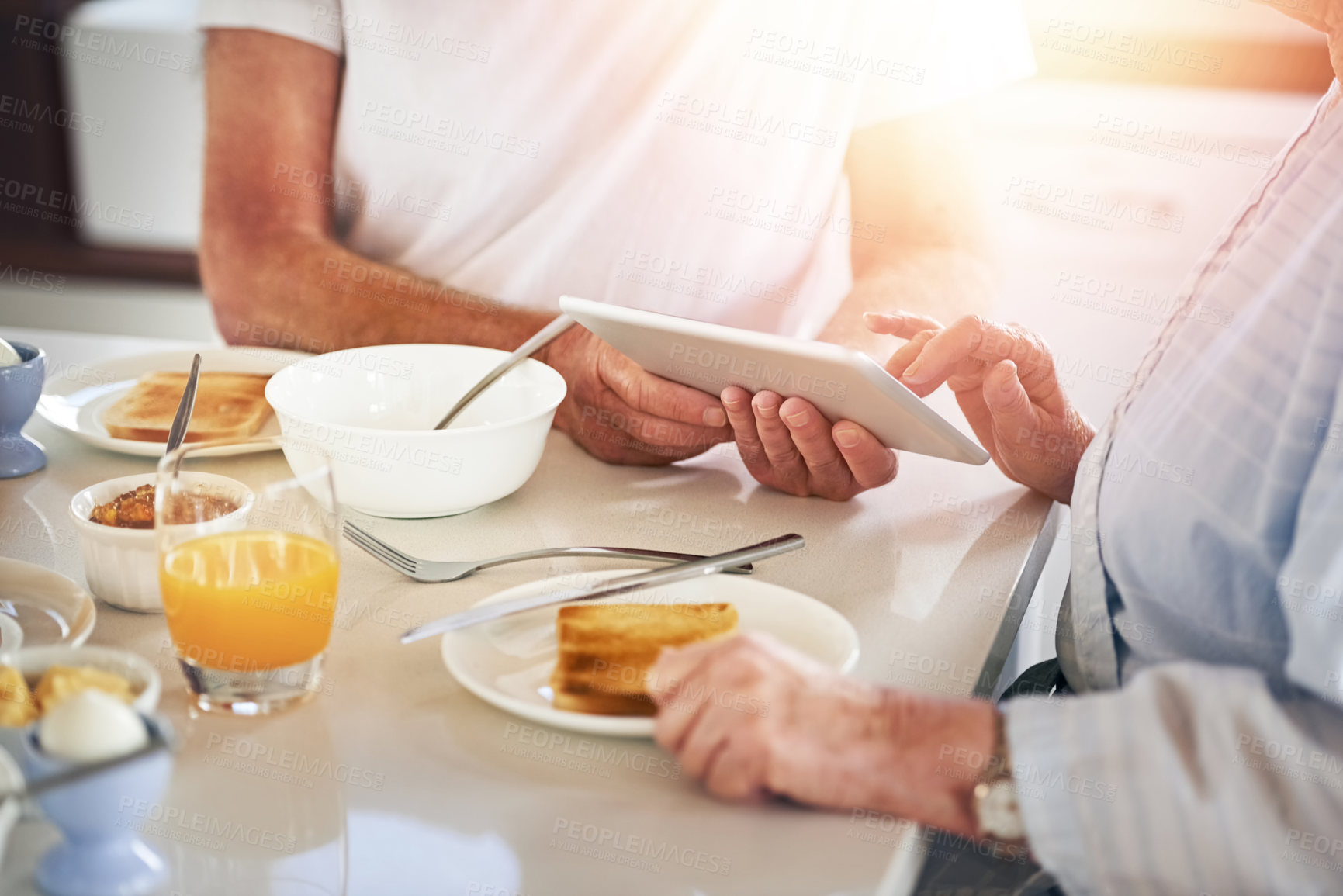 Buy stock photo Closeup shot of a senior couple using a digital tablet while having breakfast at home