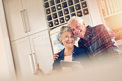 Buy stock photo Portrait of a senior couple using a digital tablet while cooking together in their kitchen at home
