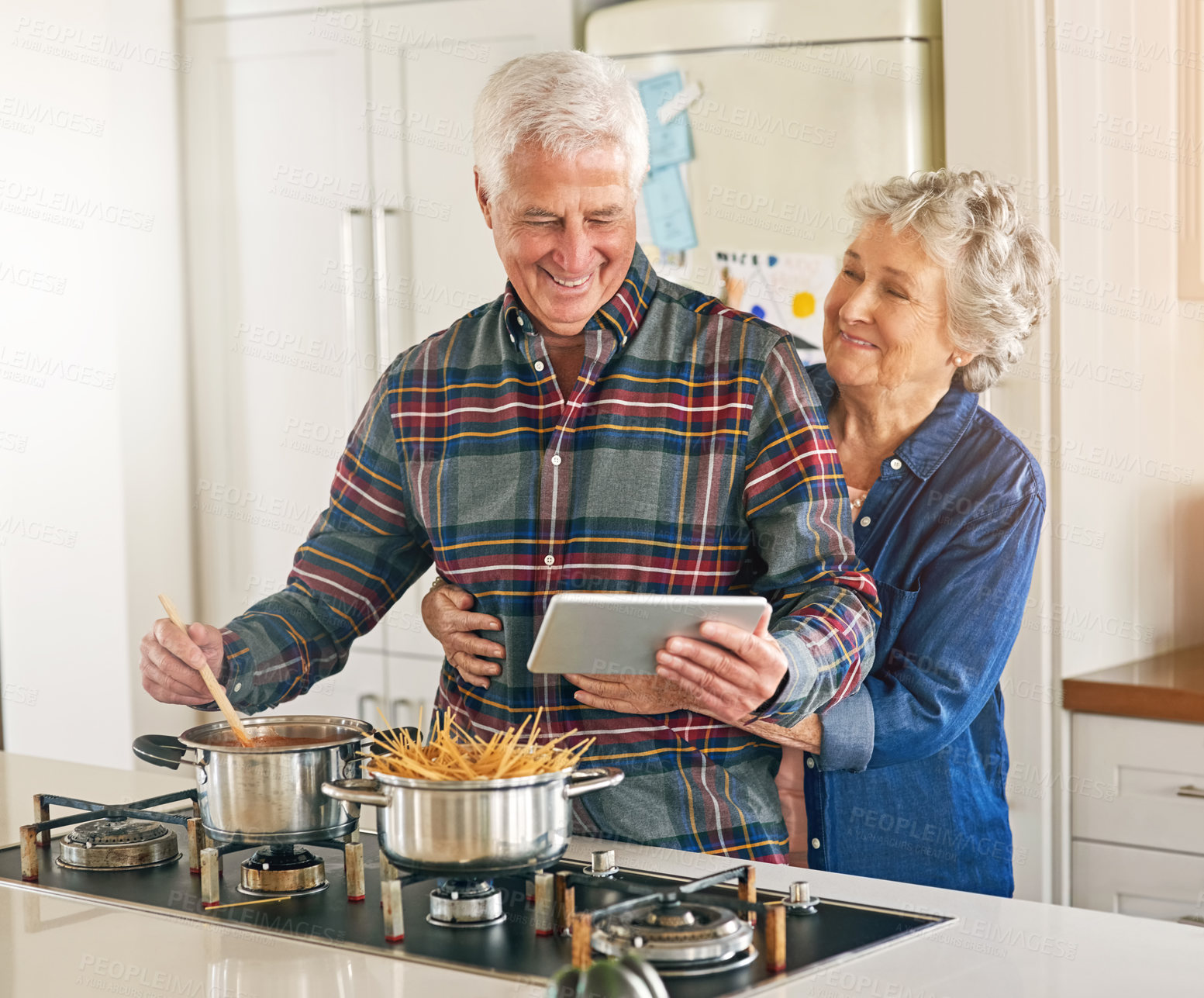 Buy stock photo Cropped shot of a senior couple using a digital tablet while cooking together in their kitchen at home