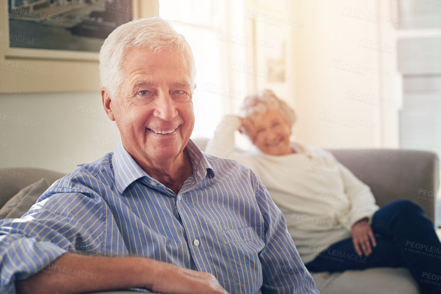 Buy stock photo Portrait of a senior man relaxing at home with his wife in the background