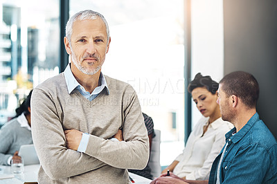 Buy stock photo Portrait of a mature businessman standing in an office with his colleagues in the background