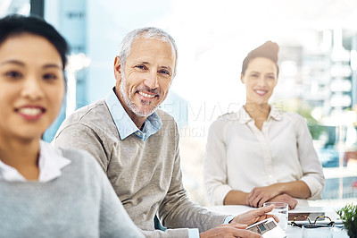 Buy stock photo Portrait of a mature businessman sitting in a meeting alongside his colleagues