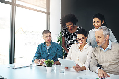 Buy stock photo Shot of a group of colleagues discussing something on a digital tablet together
