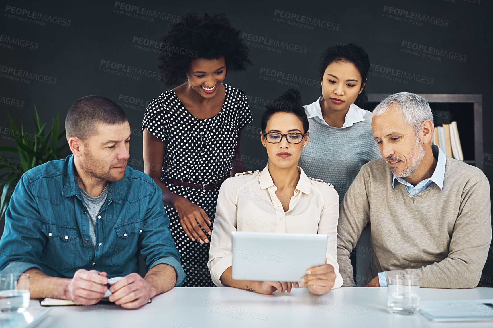 Buy stock photo Shot of a group of colleagues discussing something on a digital tablet together