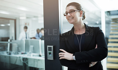 Buy stock photo Shot of a young businesswoman standing with her arms crossed in an office doorway