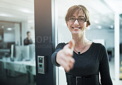 Buy stock photo Portrait of a young businesswoman offering you her hand while standing in an office doorway