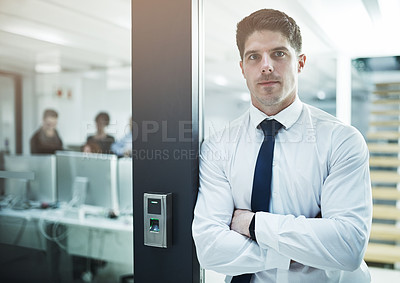 Buy stock photo Portrait of a young businessman standing with her arms crossed in an office doorway