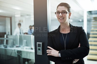Buy stock photo Portrait of a young businesswoman standing with her arms crossed in an office doorway