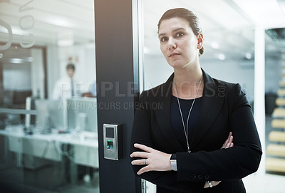 Buy stock photo Portrait of a young businesswoman standing with her arms crossed in an office doorway