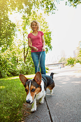 Buy stock photo Shot of an attractive young woman walking her dog in the park