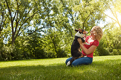 Buy stock photo Shot of a young woman bonding with her dog in the park