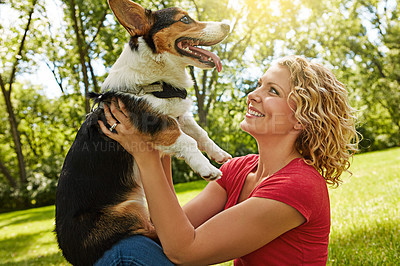 Buy stock photo Shot of a young woman bonding with her dog in the park