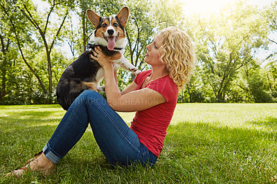 Buy stock photo Shot of a young woman bonding with her dog in the park