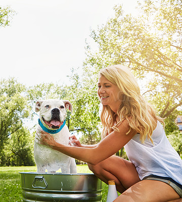 Buy stock photo Shot of a woman bathing her pet dog outside on a summer's day