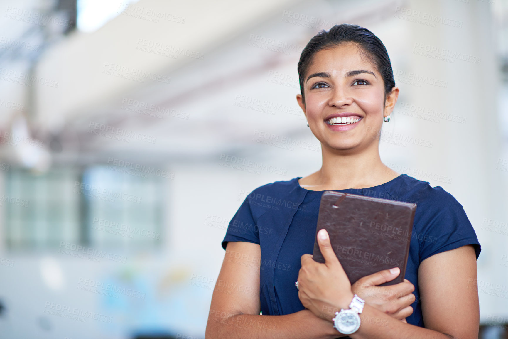 Buy stock photo Shot of an attractive young businesswoman holding her journal while standing in an office