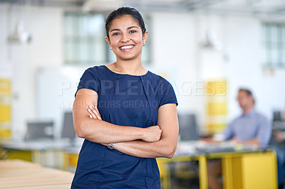 Buy stock photo Portrait of an attractive young businesswoman standing with her arms folded in the office