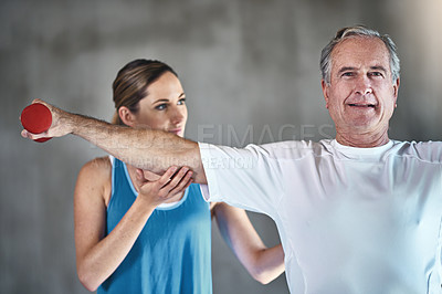 Buy stock photo Shot of a senior man using weights with the help of a physical therapist