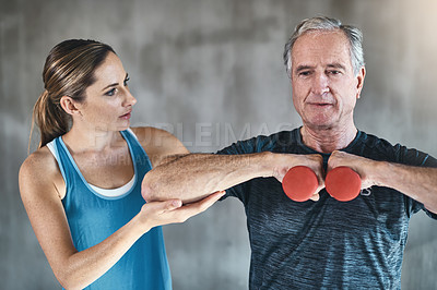 Buy stock photo Helping, dumbbell and fitness with old man and personal trainer for support, health and physiotherapy. Training, weightlifting and coaching with senior patient and female trainer for elderly workout