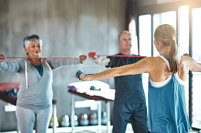 Buy stock photo Shot of a senior man and woman using resistance bands with the help of a physical therapist