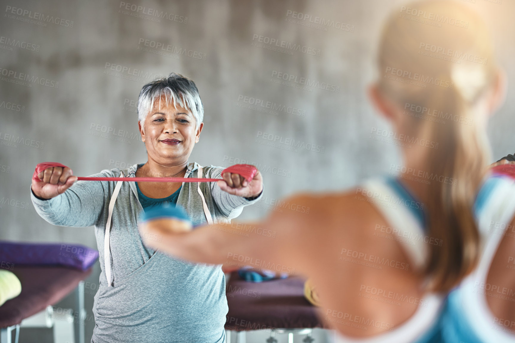 Buy stock photo Shot of a senior woman using resistance bands with the help of a physical therapist