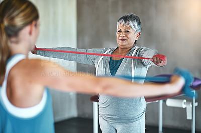 Buy stock photo Shot of a senior woman using resistance bands with the help of a physical therapist