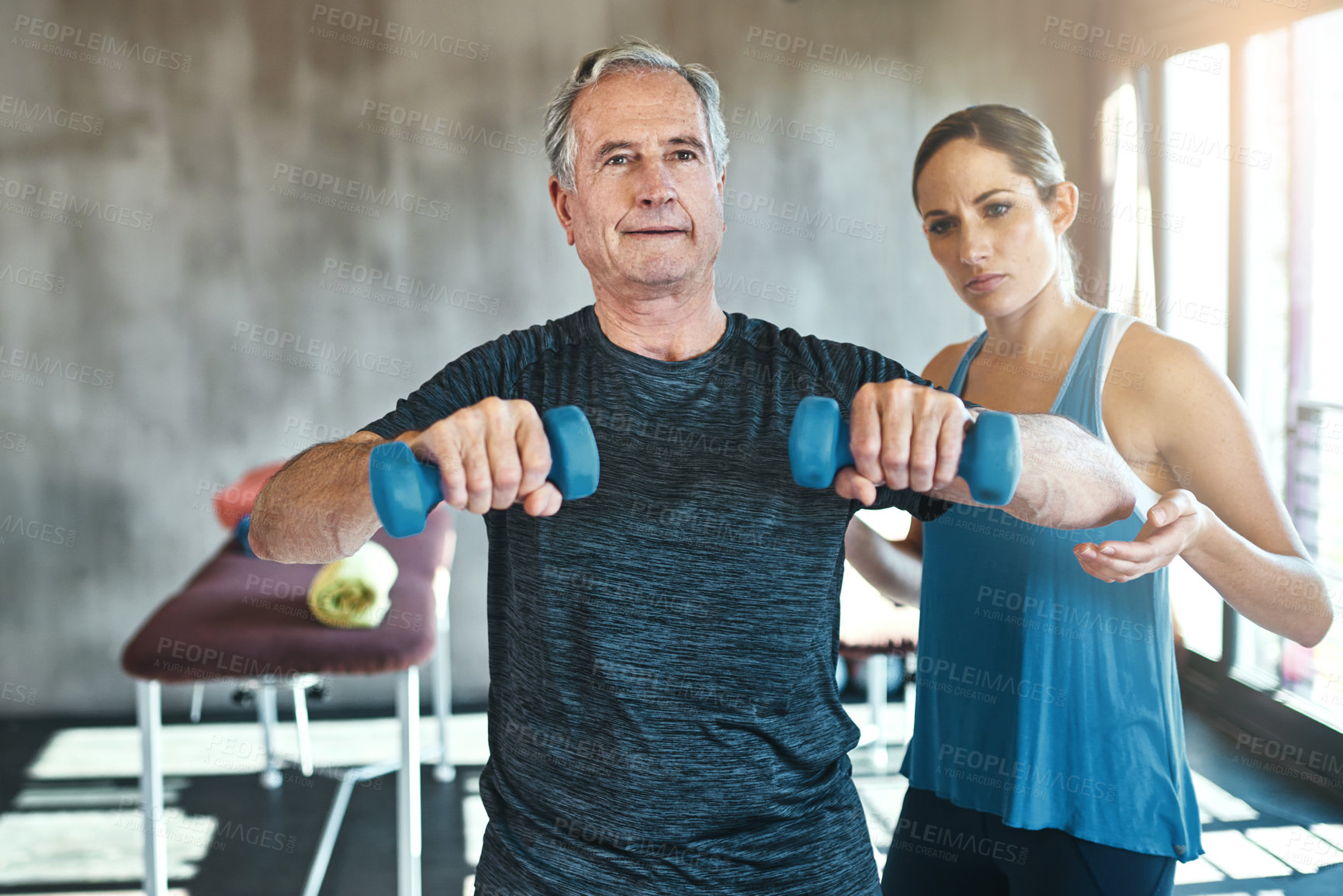 Buy stock photo Helping, dumbbell and coaching with old man and personal trainer for support, health and physiotherapy. Training, weightlifting and exercise with senior patient and female trainer for elderly workout