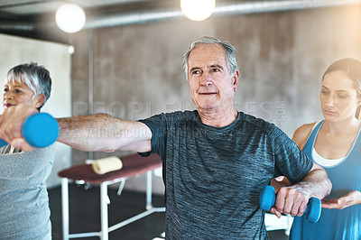 Buy stock photo Shot of a senior man and woman using weights with the help of a physical therapist