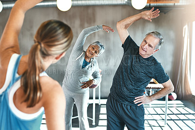 Buy stock photo Shot of a senior man and woman working out with the help of an instructor