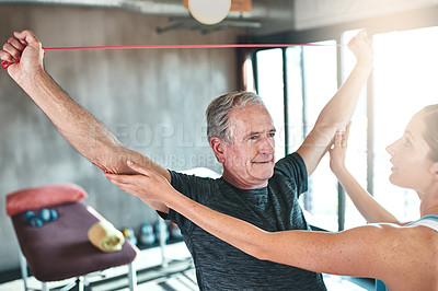Buy stock photo Shot of a senior man using resistance bands with the help of a physical therapist