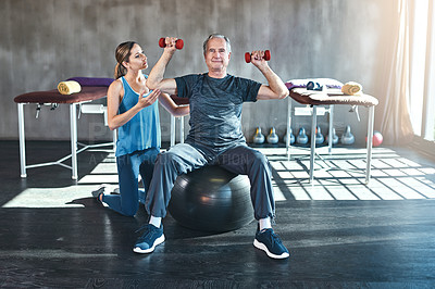 Buy stock photo Fitness, personal trainer and senior man with dumbbell in gym for physiotherapy, support or workout. Recovery, female coach and elderly patient on ball for help, arthritis balance or rehabilitation