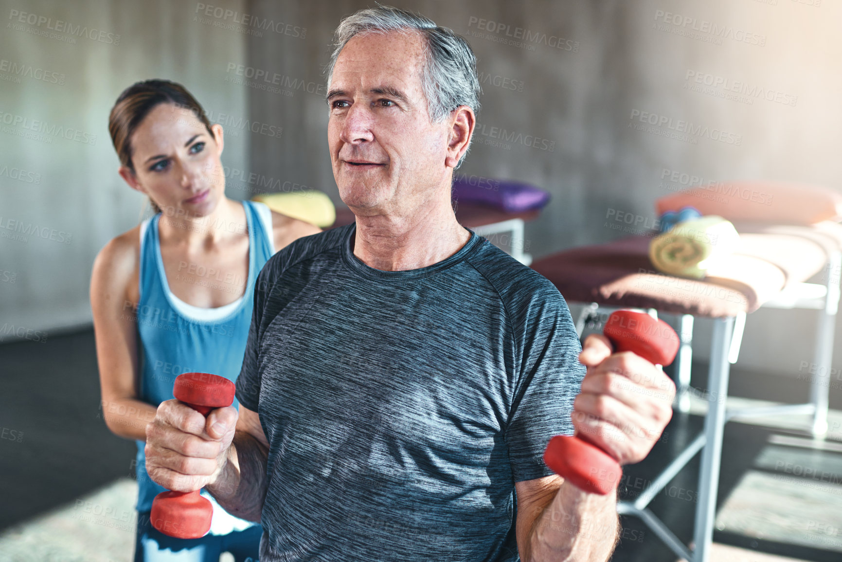Buy stock photo Physiotherapist, fitness and elderly man with dumbbell in clinic for rehabilitation, support or recovery. Lens flare, female coach and senior patient on ball for strength, balance or physiotherapy