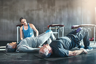 Buy stock photo Shot of two seniors working out with a physiotherapist