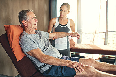Buy stock photo Shot of a senior man being treated by a physiotherapist