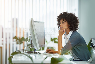 Buy stock photo Shot of a young designer deep in thought while working on a computer in a modern office