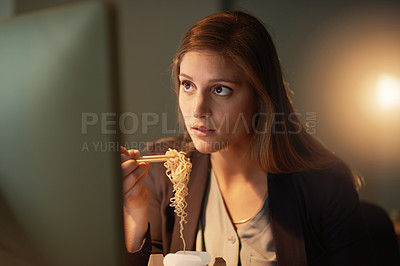 Buy stock photo Shot of a young designer eating takeaways while working late in the office
