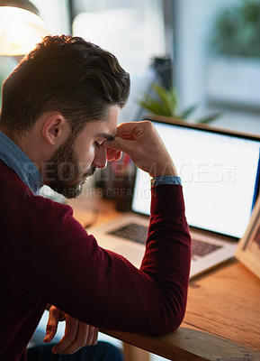 Buy stock photo Shot of a young designer battling a headache while working late in the office