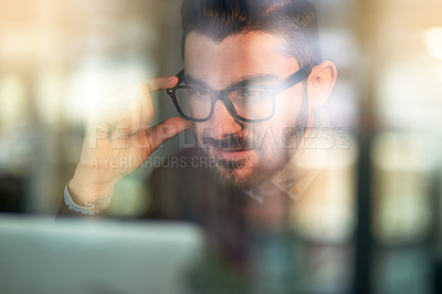 Buy stock photo Shot of a focused young programmer working on his computer behind a glass wall