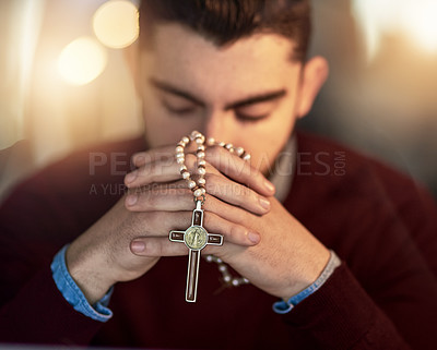Buy stock photo Shot of a young man praying on his own while holding a rosary