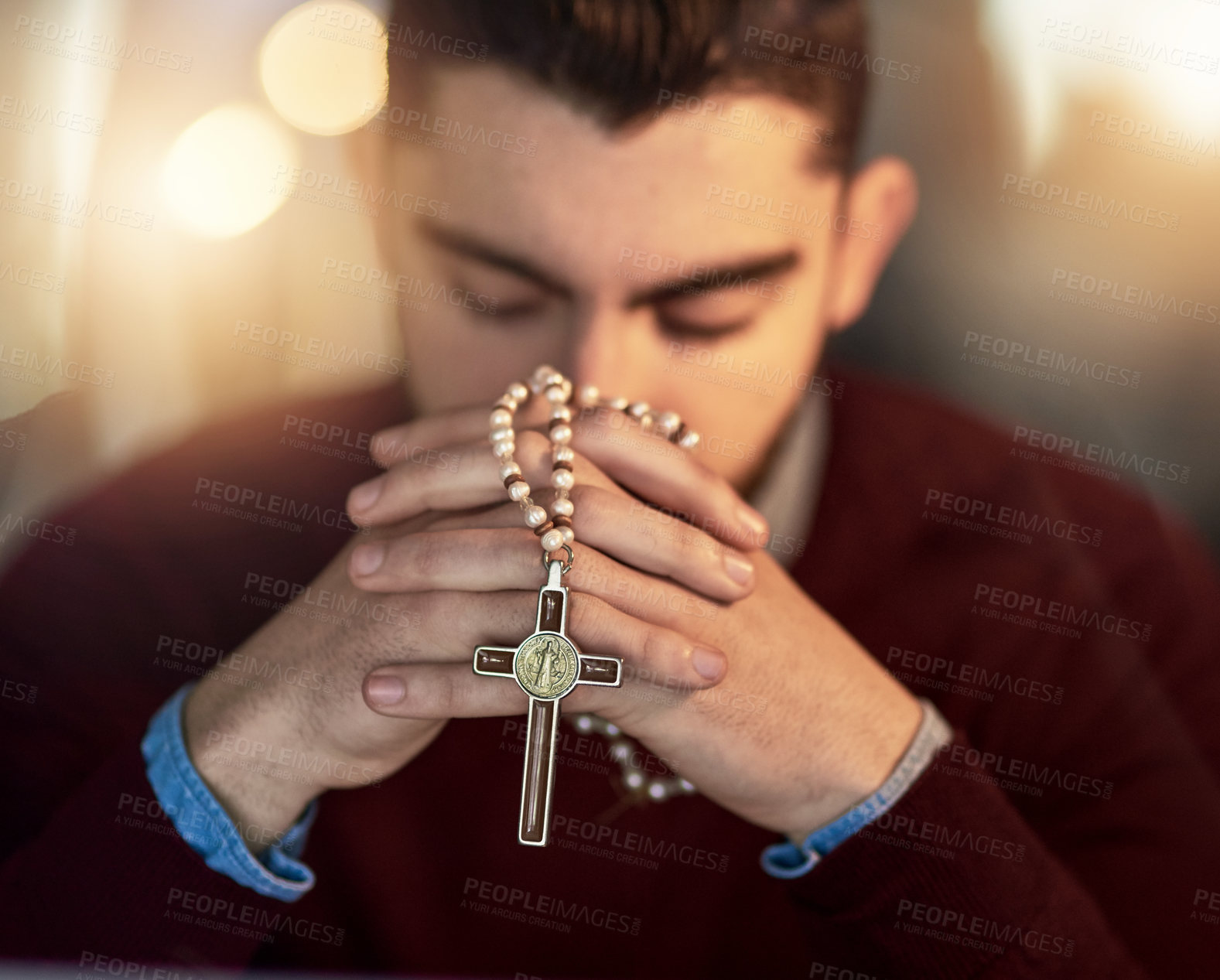 Buy stock photo Shot of a young man praying on his own while holding a rosary