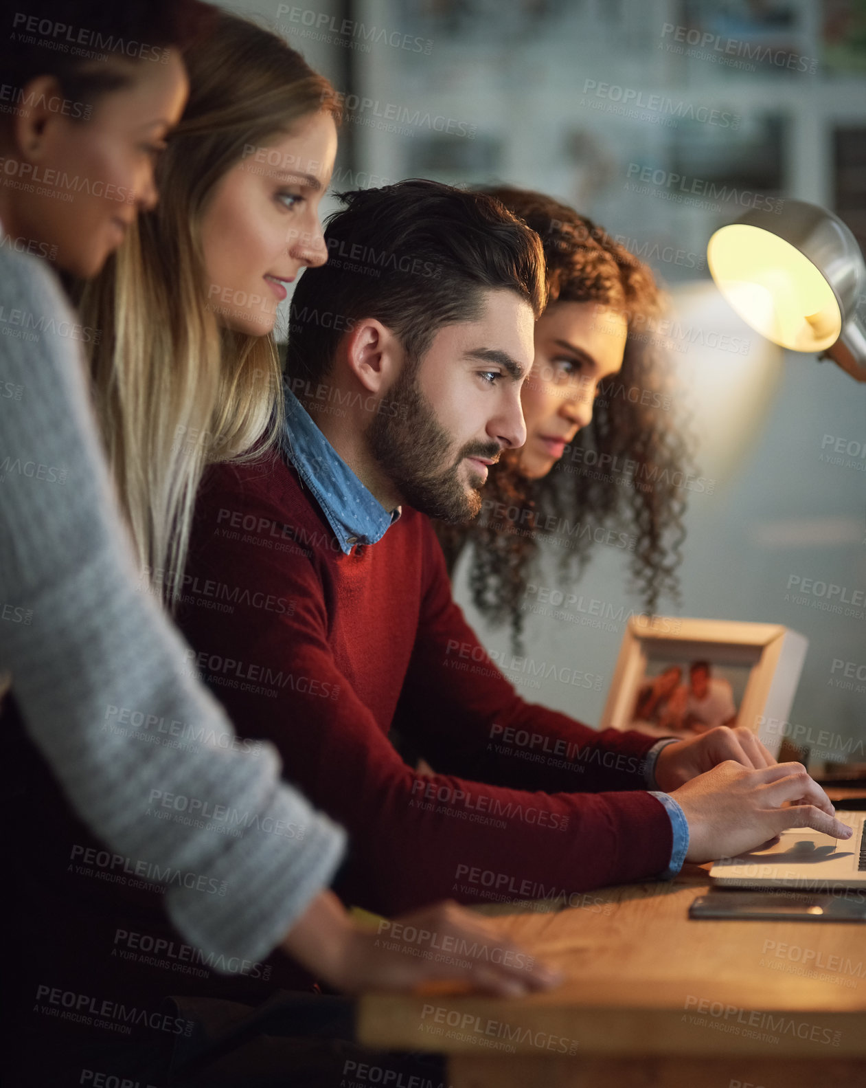 Buy stock photo Shot of a group of young entrepreneurs working late on a laptop in an office