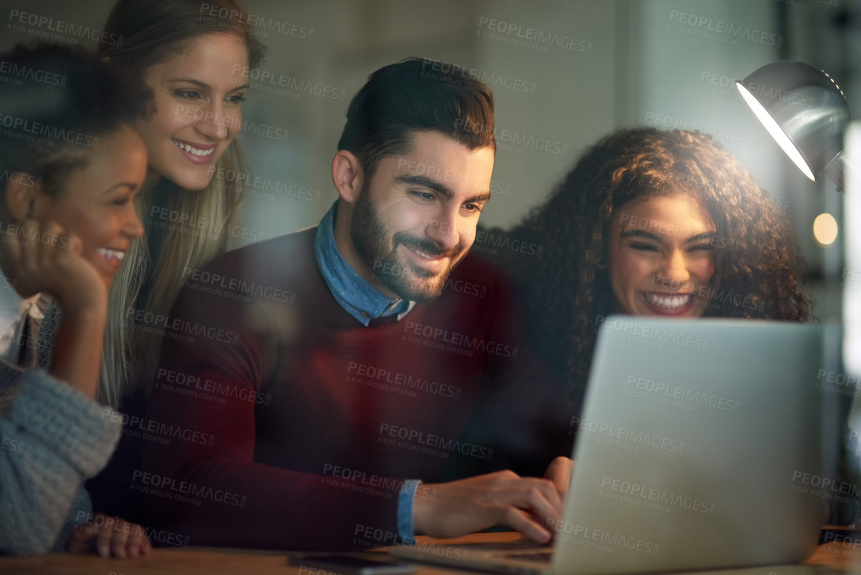 Buy stock photo Shot of a group of young entrepreneurs working late on a laptop in an office