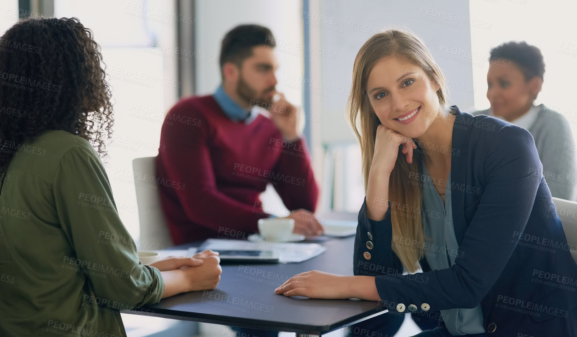 Buy stock photo Portrait of a young entrepreneur sitting in an office with her colleagues in the background