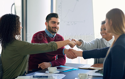 Buy stock photo Shot of a group of young entrepreneurs shaking hands during an office meeting