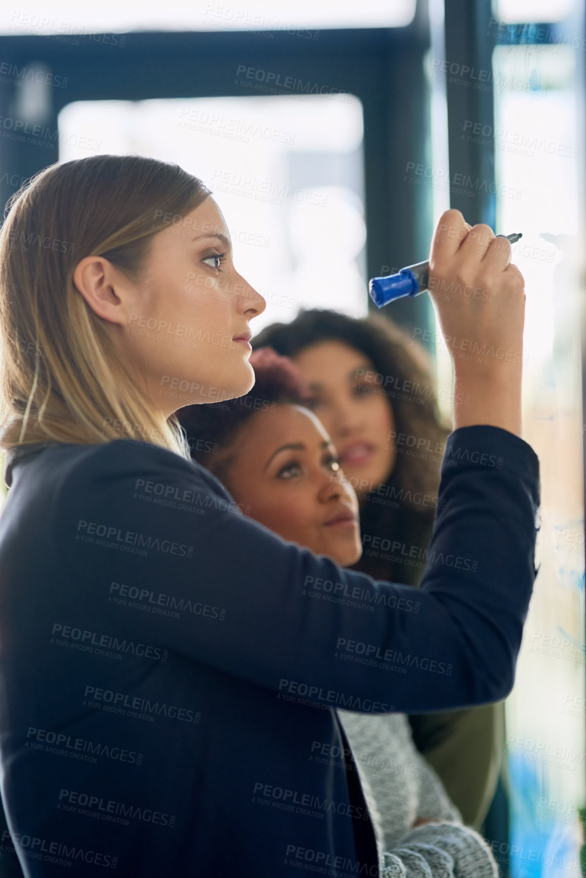 Buy stock photo Shot of a group of young entrepreneurs brainstorming with notes on a glass wall in an office